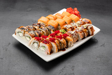 Assorted sushi rolls with salmon, sesame and glaze on white plate, restaurant serving