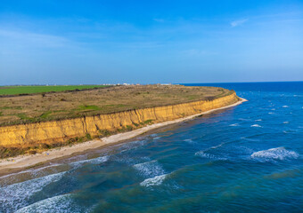 Landscape with the wild beach with a cliff from August 23, Constanta County - Romania. Steep, yellowish cliffs and turquoise sea waters