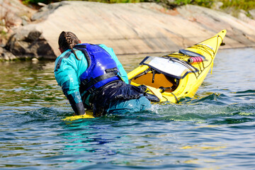 Young woman practicing self rescues while on sea kayaking expedition on Georgian Bay in fall room for text