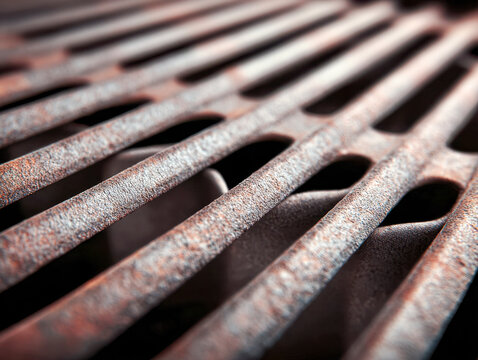 Rusty metal grill with elongated rectangular openings showing weathered texture and corrosion details in a close-up angled view - Powered by Adobe