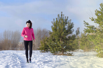 Caucasian sports woman runs in the snow in winter. Winter sports, activity