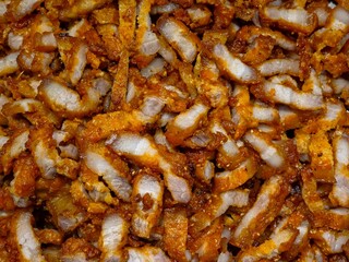 A close-up of deeply fried pork belly or crispy pork, cut into small, thick strips, filling the entire frame with a golden-brown, crunchy crust and white meat.