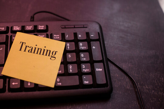 Training concept on desk background, keyboard on black table, sticky notes with text