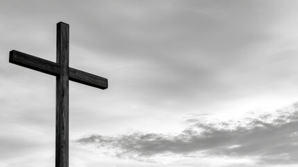 Fototapeta premium Wooden cross stands against cloudy sky, symbolizing faith and hope Black and white image features solitary cross, representing Christianity and crucifixion, set against backdrop of serene, cloudy sky
