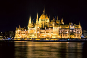 Fototapeta premium Illuminated Hungarian Parliament Building reflecting on the Danube River in Budapest during a calm night