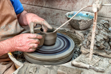 Hands shaping clay on pottery wheel during traditional ceramic crafting