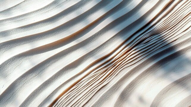 A close-up, abstract view of sand dunes or a textured surface with parallel, undulating waves. Strong, directional lighting creates deep shadows, highlighting t