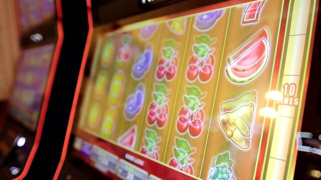 Spinning casino slot machine screen with colorful fruit and number seven symbols.