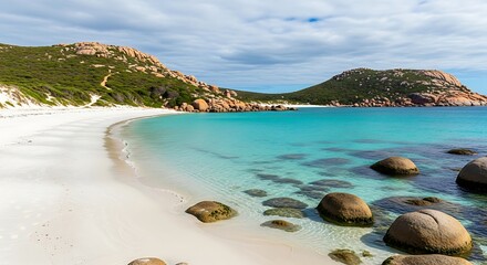 A pristine beach showcases crystal-clear turquoise waters, white sand, and rocky headlands under a partly cloudy sky