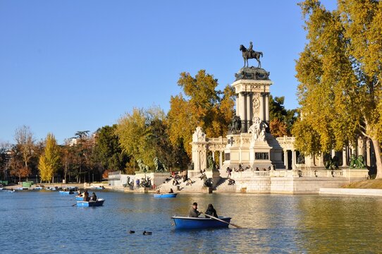 Boats on the lake at El Retiro Park in Madrid, with the Monument to Alfonso XII surrounded by autumn trees.