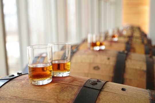 Bourbon aging setup oak barrels row sampling glasses in rustic distillery