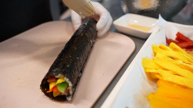 Traditional Korean Kimbap (Gimbap) Preparation: Chef Hands Cutting or Rolling the Rice Seaweed Roll (K-Food)