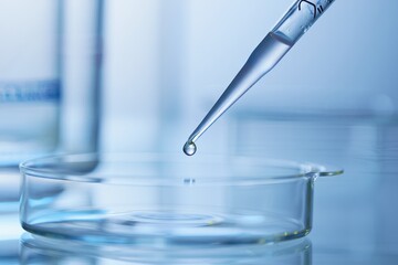 Extreme sterile pipette tip drop into glass culture dish under lab lighting