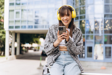 Young woman enjoying music smiling while watching smartphone