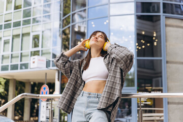 Fototapeta premium Young woman enjoying music with headphones in city