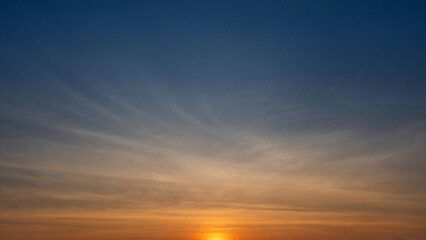 Early sunrise with warm golden tones and thin clouds spreading across the open sky.