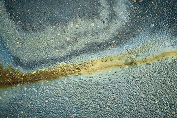 Iridescent oil spill mixing with water on asphalt creating a colorful background