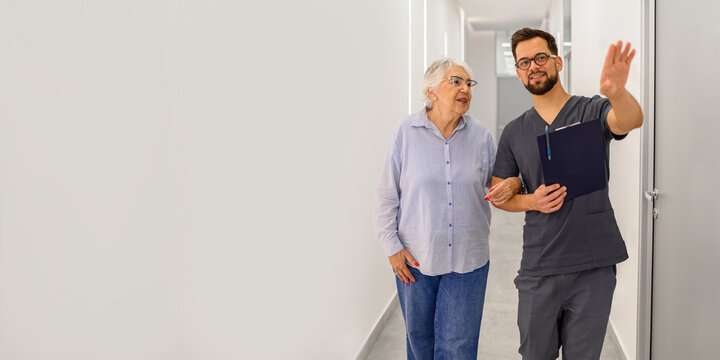 Male doctor walking with senior patient in hospital corridor reviewing medical results and explaining treatment during visit