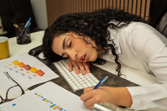 Businesswoman experiencing burnout sleeping at office desk