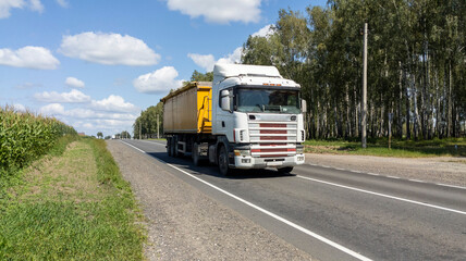 Scenic front view modern white semi-trailer truck driving forest road . Freight cargo logistics transportation vehicle freeway