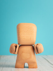 Wooden toy figure standing with arms bent on blue background