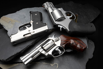 Revolver and automatic handgun on black stone background