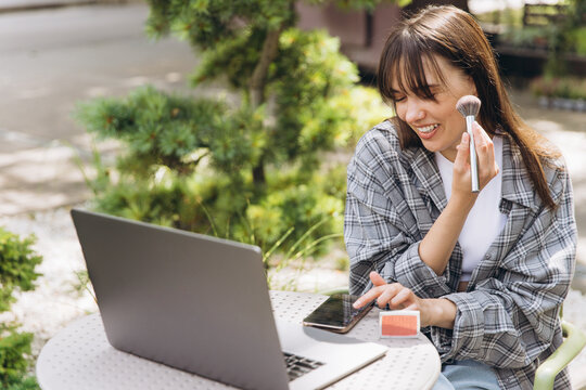 Woman creating online beauty content with makeup outdoors