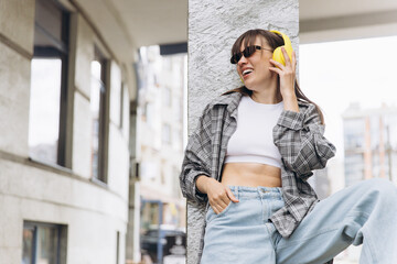 Fototapeta premium Young woman enjoying music with yellow headphones outdoors