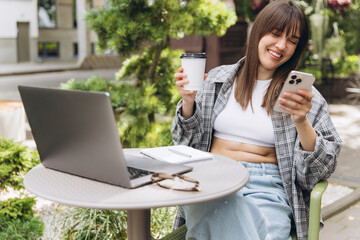 Woman working remotely at outdoor cafe using smartphone