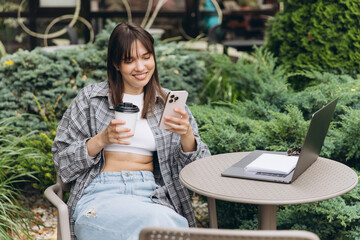 Young woman enjoying remote work outdoors with coffee