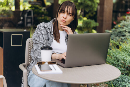Woman thinking while working on laptop outdoors