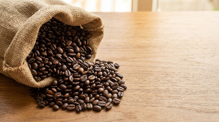 Roasted Coffee Beans Spilling from Burlap Bag onto Wooden Table