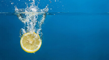 Yellow Lemon Slice Dropping into Water Splash on Blue Background