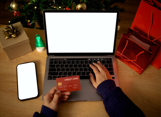 Holiday online shopping on laptop with credit card and smartphone supporting secure digital payments festive e-commerce purchases seamless checkout processes seasonal consumer behavior