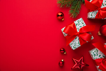 Merry Christmas and Happy Holidays greeting card, frame, banner. New Year. White, red Christmas ornaments and gifts on red background top view. Winter xmas festive holiday theme.