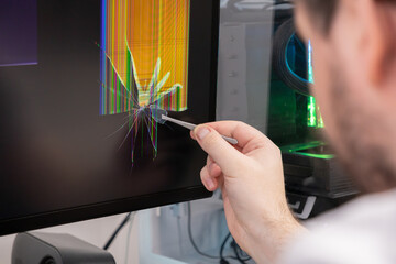 Skilled technician's hand expertly uses tweezers to remove a tiny glass shard from a severely cracked computer monitor, demonstrating essential electronic device repair