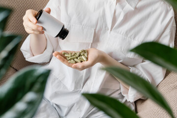 Obraz premium Woman taking daily herbal capsules for wellness and health