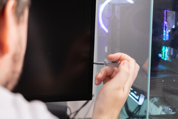 Technician's hand using a precise voltage tester tool on a computer monitor, symbolizing detailed electronics diagnostics, complex hardware troubleshooting, and expert repair