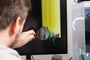 Technician inspecting a cracked computer monitor screen showing colorful lines with a magnifying glass, symbolizing electronic device repair and tech support