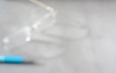 Blurred gray background with eyeglasses and pen
