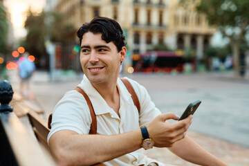Young man enjoys sunny day while using smartphone in urban setting, highlighting his joy and connection to the world around him