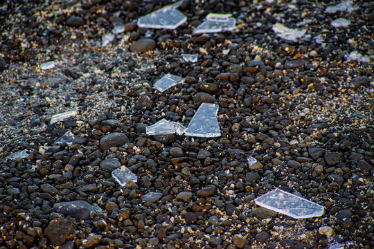 Broken Glass Pieces Scattered on Rocky Beach Surface