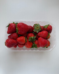 Bright ripe strawberries packed neatly inside plastic box.