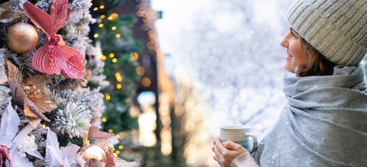 Woman with hot mug is watching on a christmas tree