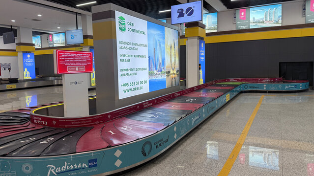 Batumi, Georgia - October 20, 2025: Baggage claim area with colorful carousel and advertising screens at the airport