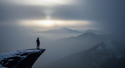 Man on cliff edge gazes at misty mountain range at sunrise