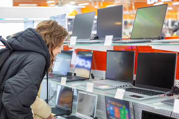 Young girl choosing laptop at a supermarket shopping mall