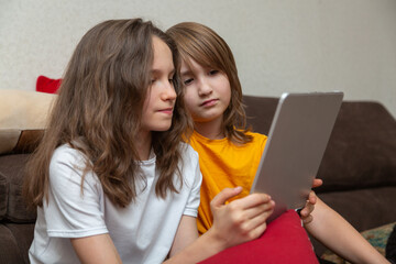 Young girls using a tablet on the sofa at home