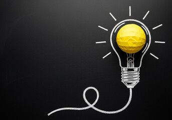 A crumpled paper lightbulb drawn on a chalkboard with ample copy space, a professional concept perfect for presenting new ideas and creative strategies