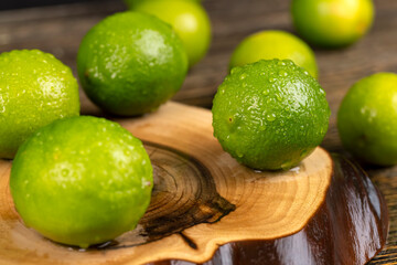 wet green ripe limes scattered on the wooden table in the kitchen, ripe and juicy lime fruits for cooking, green limes covered with drops of water